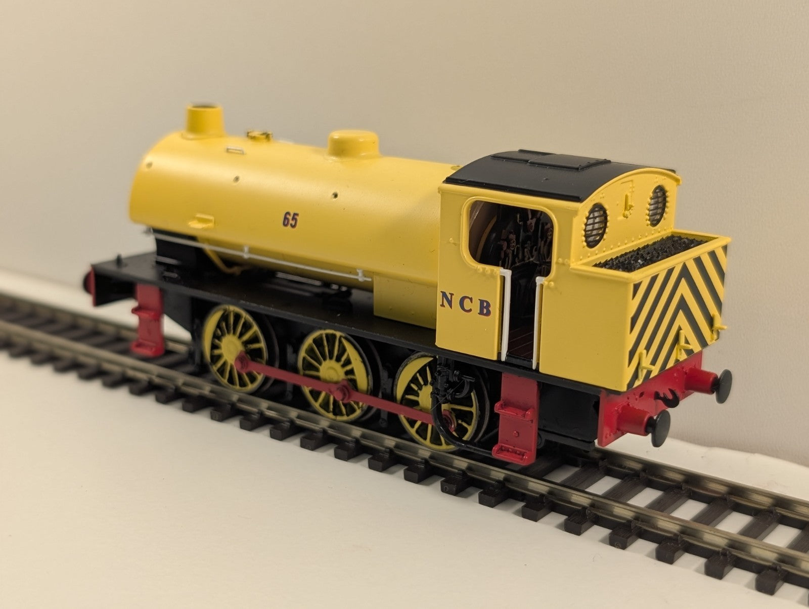 Yellow model train with black and yellow striped rear, red accents, and NCB text on the side
