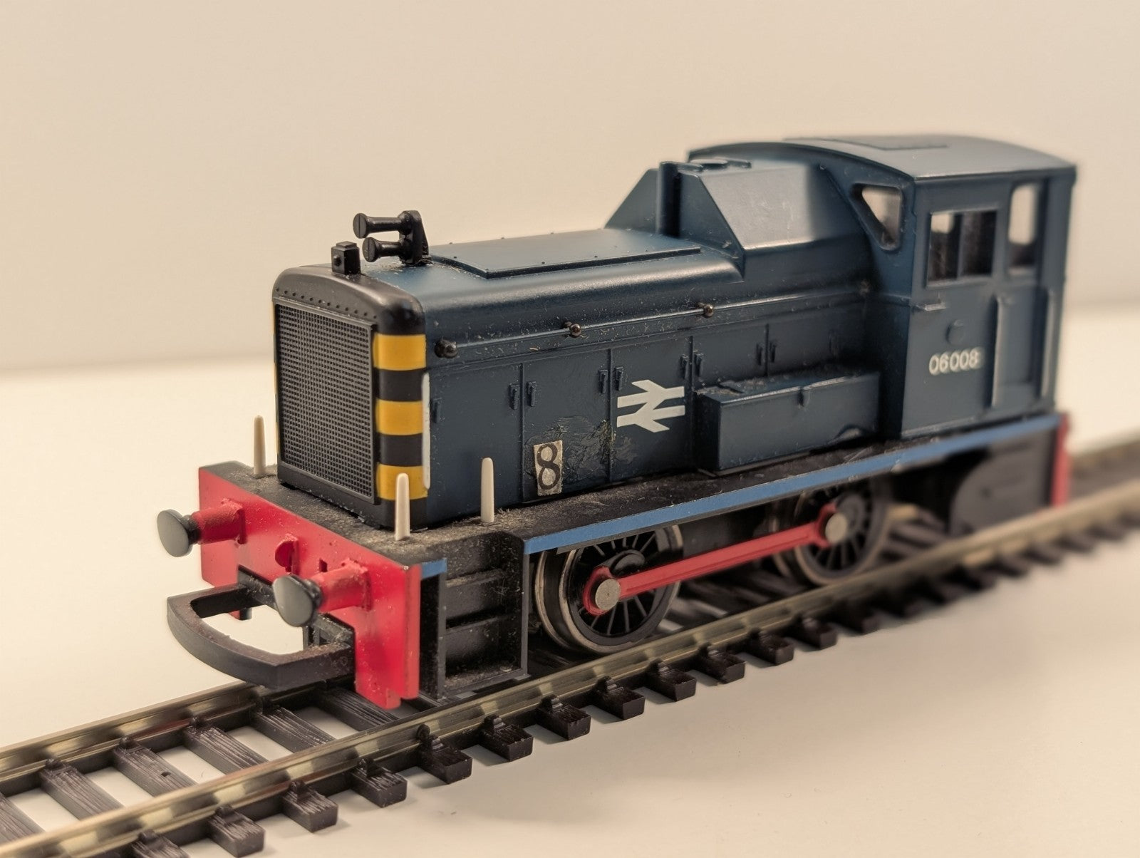 Blue model train engine with yellow and black striped front, red bumper, and white British Rail logo